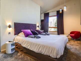 Experience luxury in this stunning bedroom! Featuring a plush bed with vibrant purple accents, this space is designed for ultimate comfort.