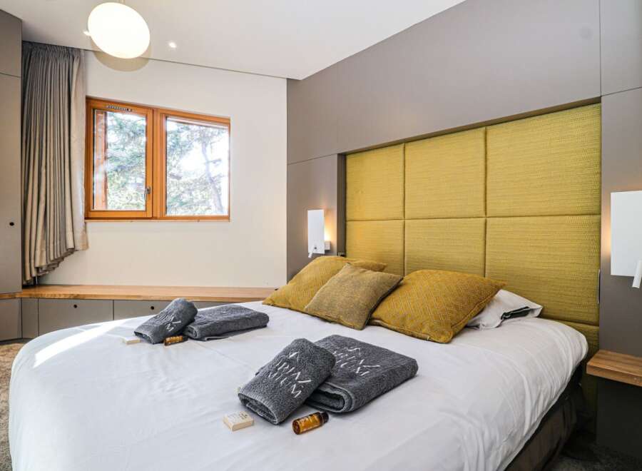 Experience luxury in this stunning bedroom featuring a plush, yellow headboard and a comfortable bed.