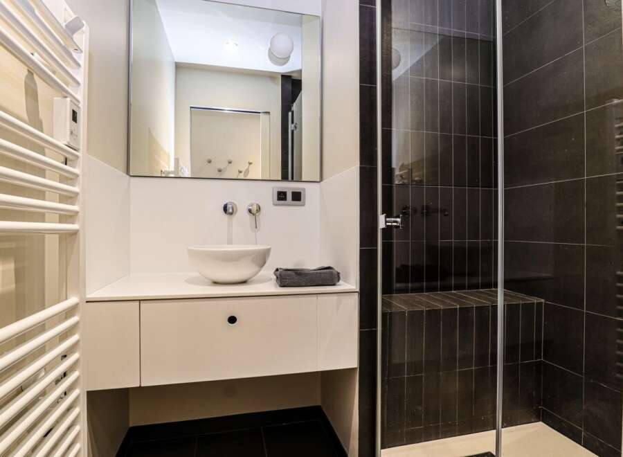 This modern bathroom features a sleek design with a white vanity and a stylish vessel sink.