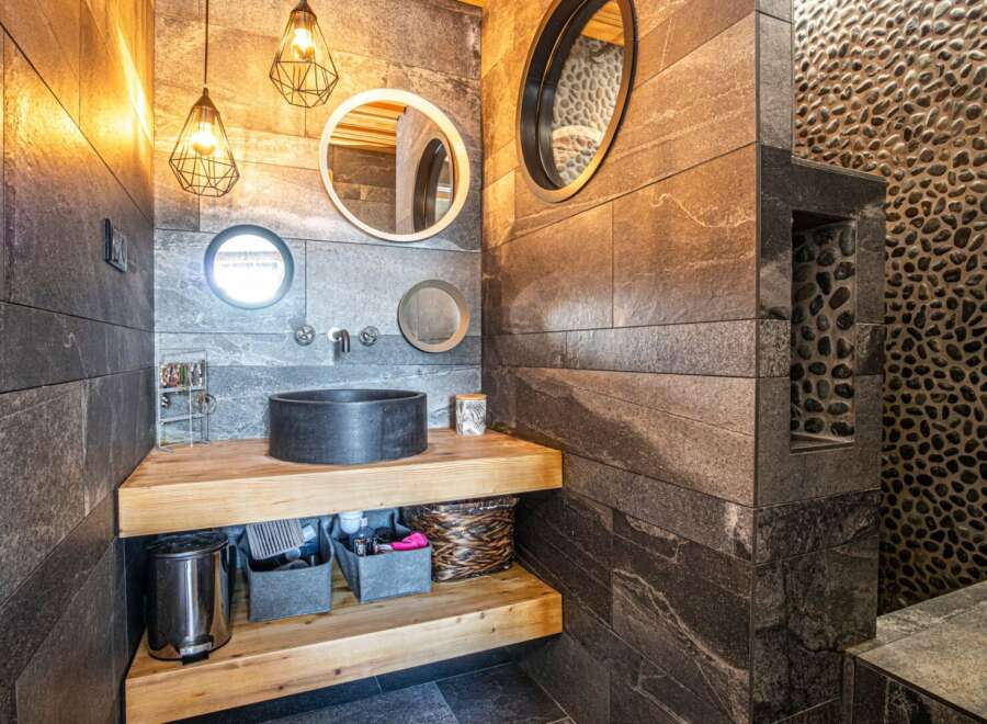 This stunning bathroom boasts a unique design with a sleek black sink and stylish lighting fixtures.