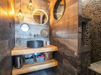 This stunning bathroom boasts a unique design with a sleek black sink and stylish lighting fixtures.