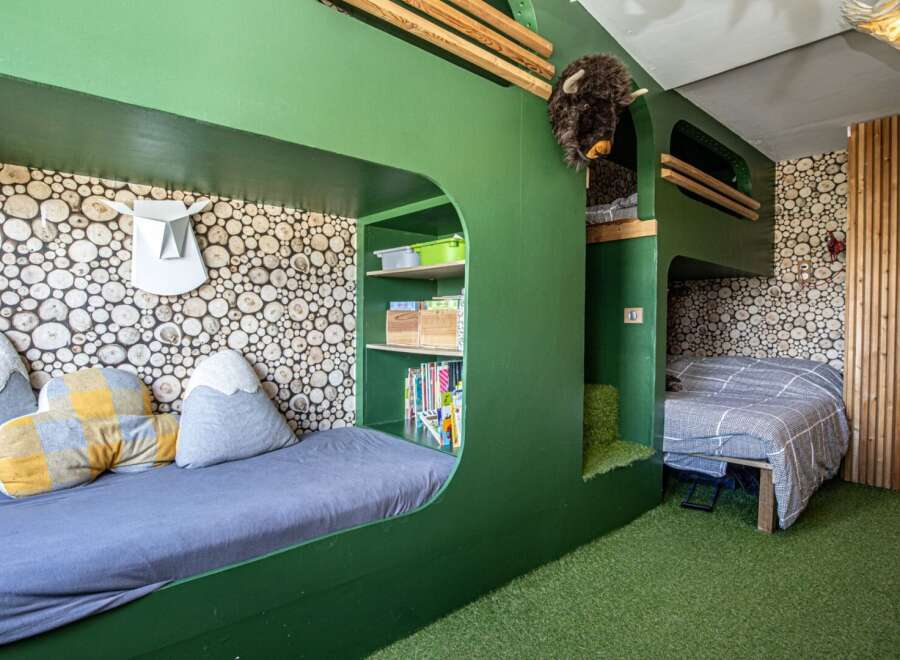 Discover a unique and playful bedroom design, perfect for kids! This space features custom-built bunk beds with a fun, green color scheme and cozy reading nooks.