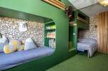 Discover a unique and playful bedroom design, perfect for kids! This space features custom-built bunk beds with a fun, green color scheme and cozy reading nooks.