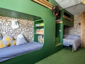 Discover a unique and playful bedroom design, perfect for kids! This space features custom-built bunk beds with a fun, green color scheme and cozy reading nooks.