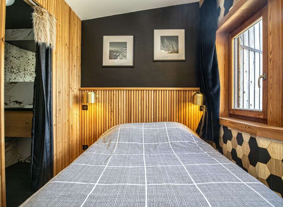 Experience the cozy charm of this bedroom, featuring a stylish wooden headboard and warm lighting.