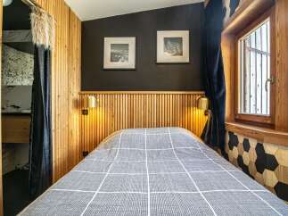Experience the cozy charm of this bedroom, featuring a stylish wooden headboard and warm lighting.