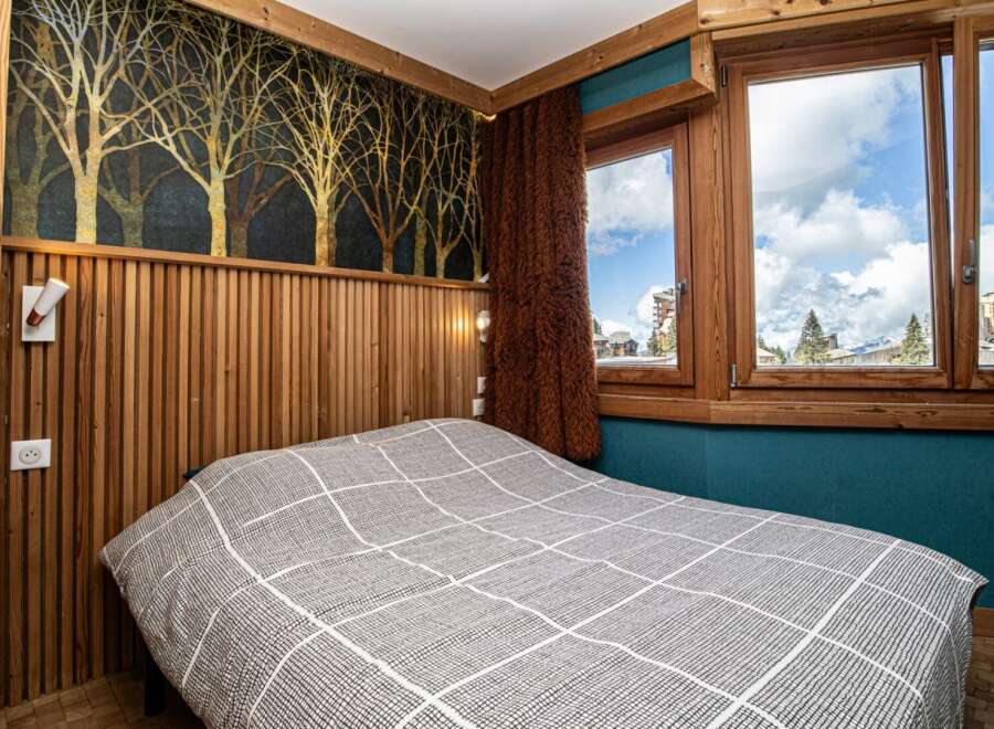 Experience the charm of this cozy bedroom featuring a unique wooden accent wall and a stylish bedspread.