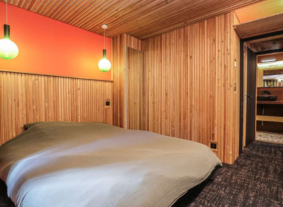 This cozy bedroom features a unique wooden paneling design, creating a warm and inviting atmosphere.