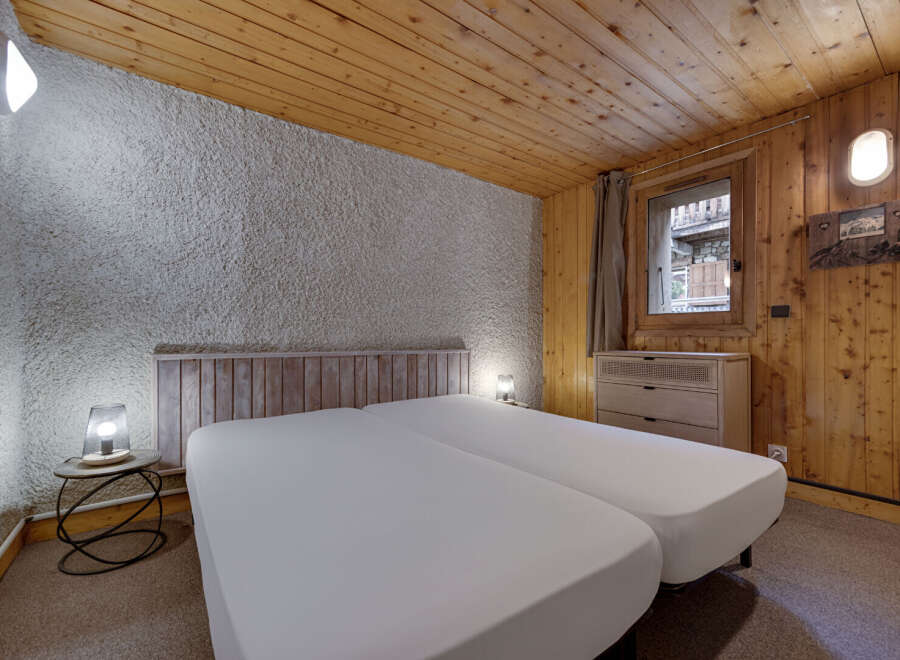 This cozy bedroom features a rustic design with wooden paneling and a textured wall.