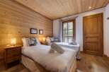This cozy bedroom features a warm wooden ceiling and walls, creating a rustic and inviting atmosphere.