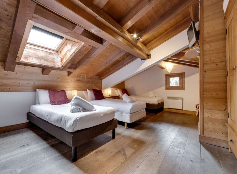 Discover the charm of this stunning bedroom, featuring a unique sloped ceiling and exposed wooden beams that add character and warmth.