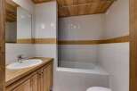 This bathroom features a clean and modern design with white tiles and a wooden vanity.