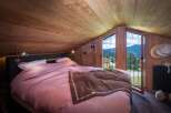 Experience the charm of this cozy bedroom, featuring a warm wooden interior and a stunning mountain view from the balcony.