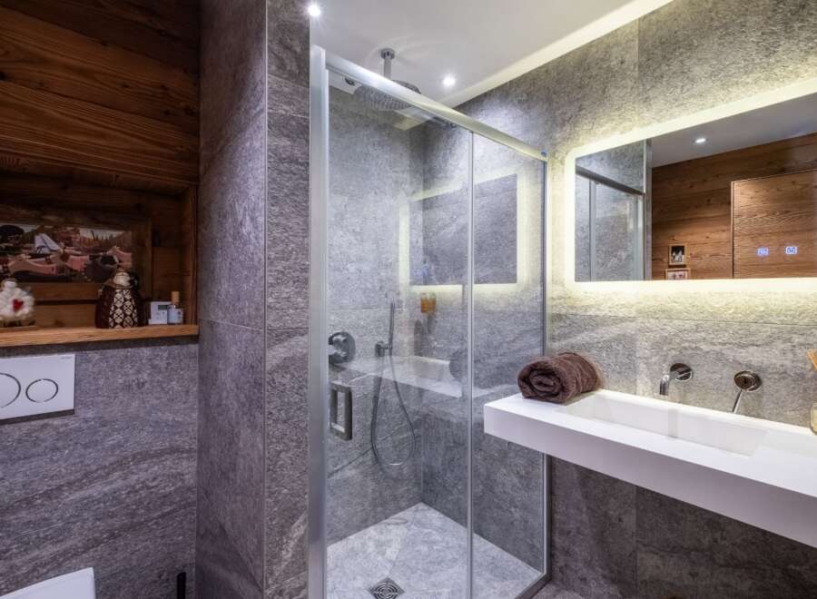 Step into luxury with this stunning bathroom featuring a modern glass shower and sleek white sink.