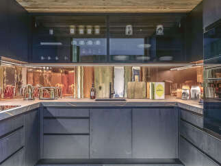 This modern kitchen boasts a sleek design with dark cabinetry and a stunning copper backsplash, creating a warm and inviting atmosphere.