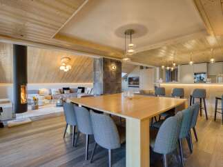 Experience luxury living in this stunning property featuring a modern dining area with a sleek wooden table and stylish chairs.