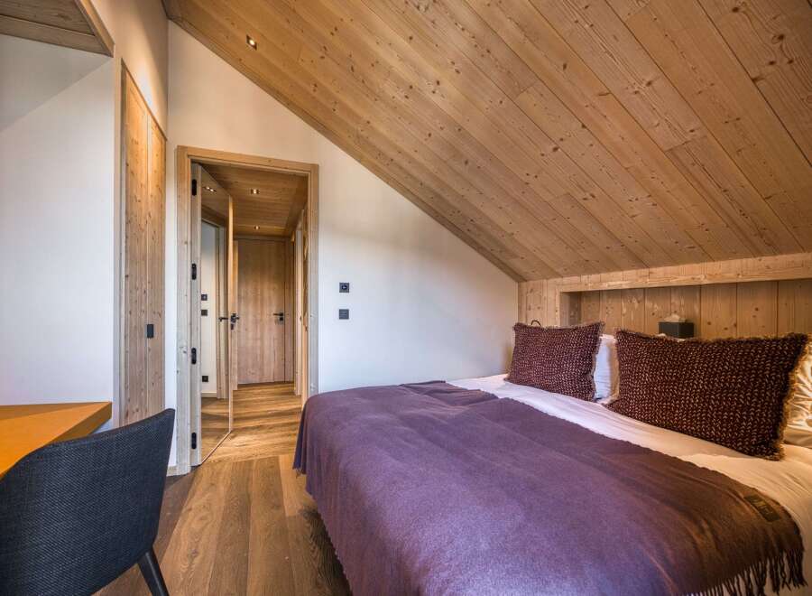Experience the charm of this cozy bedroom, featuring a warm wooden ceiling and walls that create a rustic ambiance.