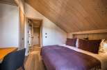 Experience the charm of this cozy bedroom, featuring a warm wooden ceiling and walls that create a rustic ambiance.