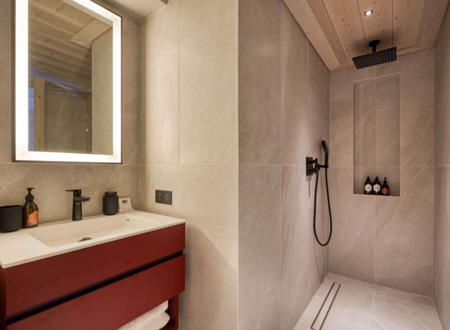 Step into luxury with this stunning bathroom, featuring a sleek red vanity and a modern, illuminated mirror.