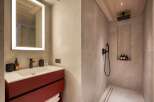 Step into luxury with this stunning bathroom, featuring a sleek red vanity and a modern, illuminated mirror.