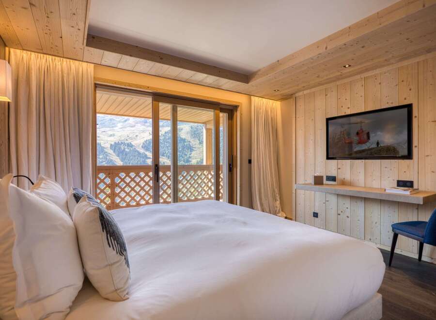 Experience luxury in this stunning bedroom featuring a cozy wooden interior and a breathtaking mountain view.