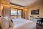 Experience luxury in this stunning bedroom featuring a cozy wooden interior and a breathtaking mountain view.
