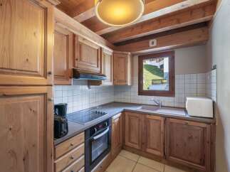 This charming kitchen features wooden cabinetry and a cozy ambiance, perfect for preparing meals.