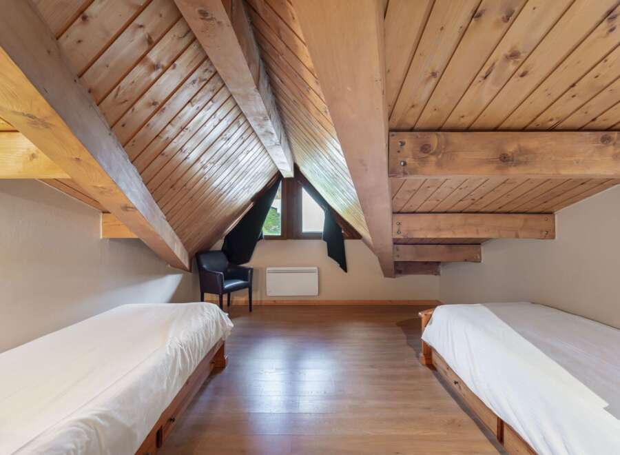 Discover the charm of this unique attic bedroom, featuring exposed wooden beams and a cozy atmosphere.
