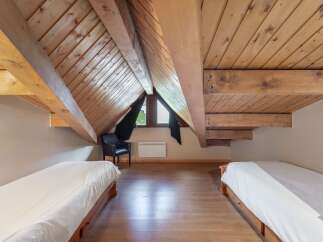 Discover the charm of this unique attic bedroom, featuring exposed wooden beams and a cozy atmosphere.