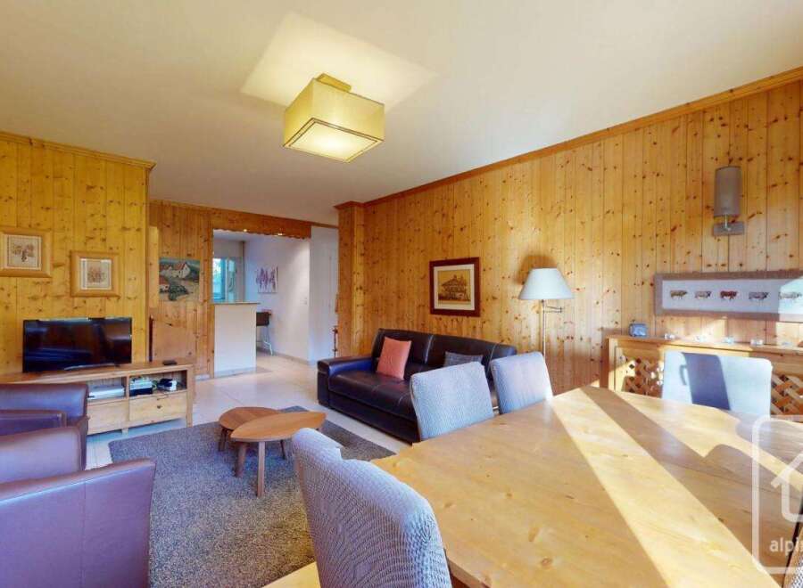 Discover the charm of this inviting property, featuring a cozy living area with warm wooden paneling and a comfortable seating arrangement.