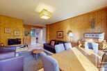 Discover the charm of this inviting property, featuring a cozy living area with warm wooden paneling and a comfortable seating arrangement.