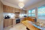 This stunning kitchen boasts a modern design with sleek wooden cabinetry and granite countertops, creating a warm and inviting atmosphere.