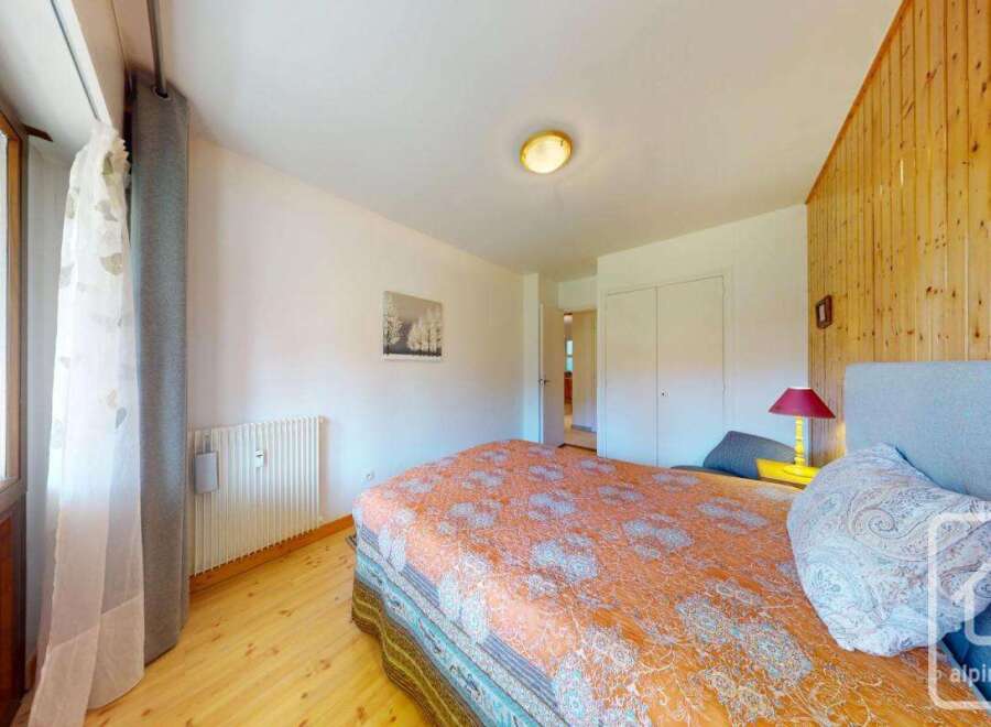 Discover the charm of this cozy bedroom, featuring a comfortable bed and a warm wooden accent wall.