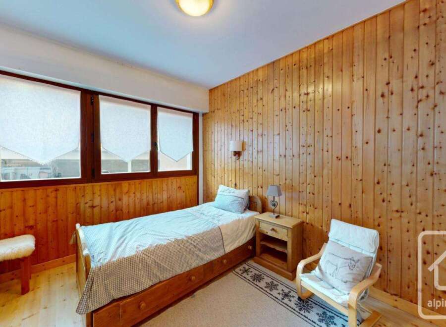 Discover the charm of this cozy bedroom featuring wooden paneling and a comfortable single bed.