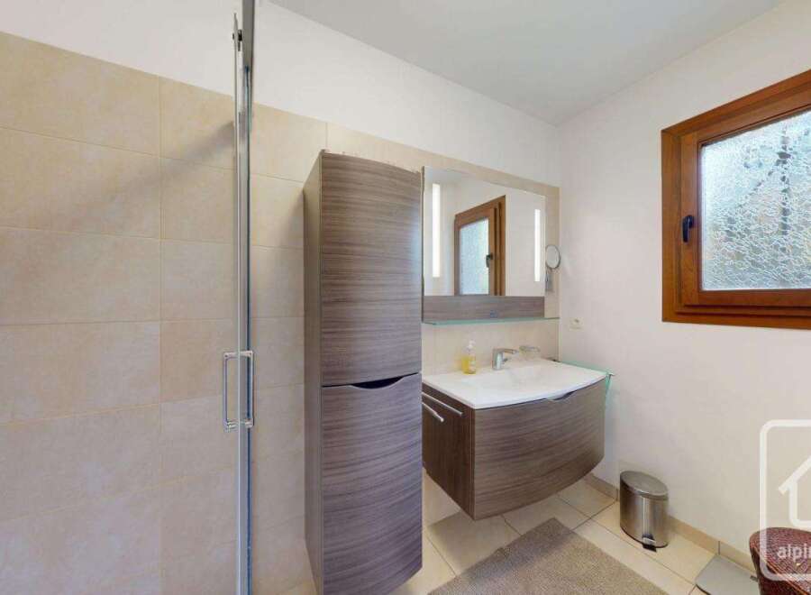 This modern bathroom features a stylish vanity with a sleek design, complemented by a large mirror and built-in lighting.