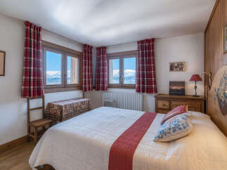 This charming bedroom offers stunning mountain views through its large windows, creating a serene and inviting atmosphere.