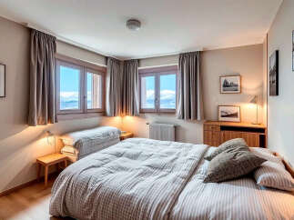 Experience the tranquility of this charming bedroom, featuring stunning mountain views through large windows.