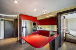 This modern kitchen boasts sleek red cabinetry and stainless steel appliances, creating a vibrant and stylish space.
