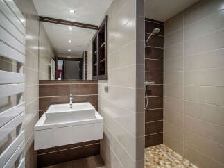 This modern bathroom features a sleek design with a floating sink and a walk-in shower.