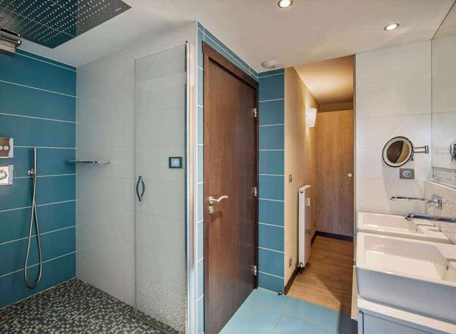 Step into this modern bathroom, featuring a sleek glass shower enclosure and stylish blue tile accents.