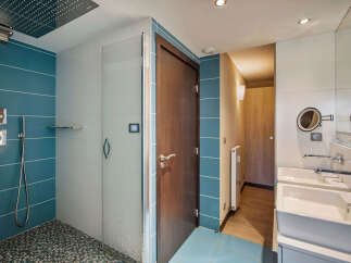 Step into this modern bathroom, featuring a sleek glass shower enclosure and stylish blue tile accents.