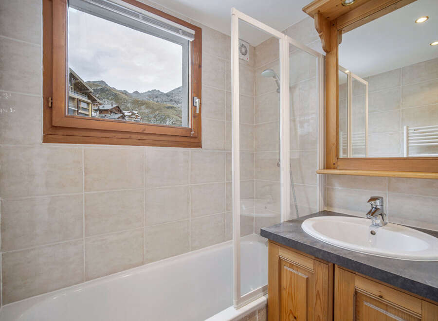 This charming bathroom features a stunning view of the mountains through a large window.