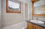 This charming bathroom features a stunning view of the mountains through a large window.