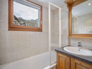 This charming bathroom features a stunning view of the mountains through a large window.