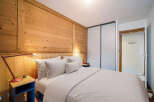 Experience the warmth of this cozy bedroom featuring stunning wooden paneling and a comfortable bed.