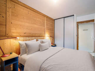 Experience the warmth of this cozy bedroom featuring stunning wooden paneling and a comfortable bed.