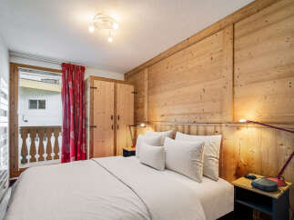 Experience the charm of this cozy bedroom featuring a rustic wooden accent wall and a comfortable bed with plush pillows.