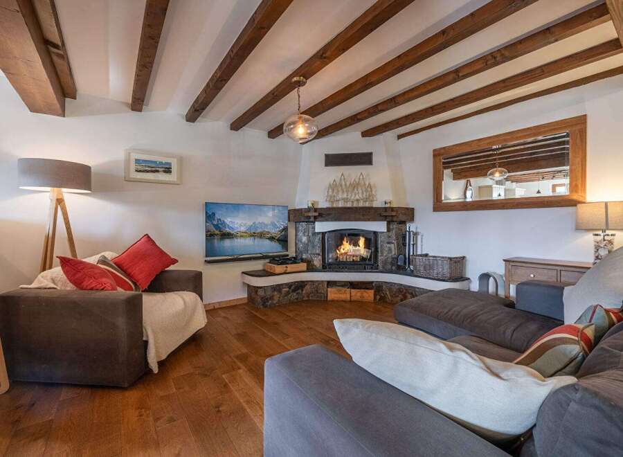 Experience the warmth of this stunning living room, featuring a cozy fireplace and exposed wooden beams.