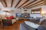 Experience the warmth of this stunning living room, featuring a cozy fireplace and exposed wooden beams.