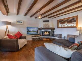 Experience the warmth of this stunning living room, featuring a cozy fireplace and exposed wooden beams.